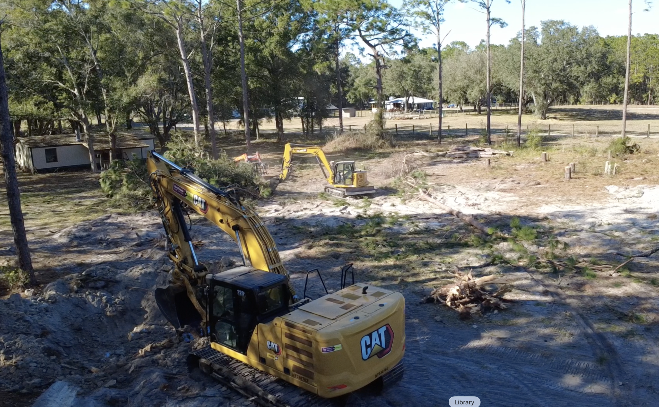 Two Cat excavators providing land clearing services removing trees and brush for site preparation in Central Florida