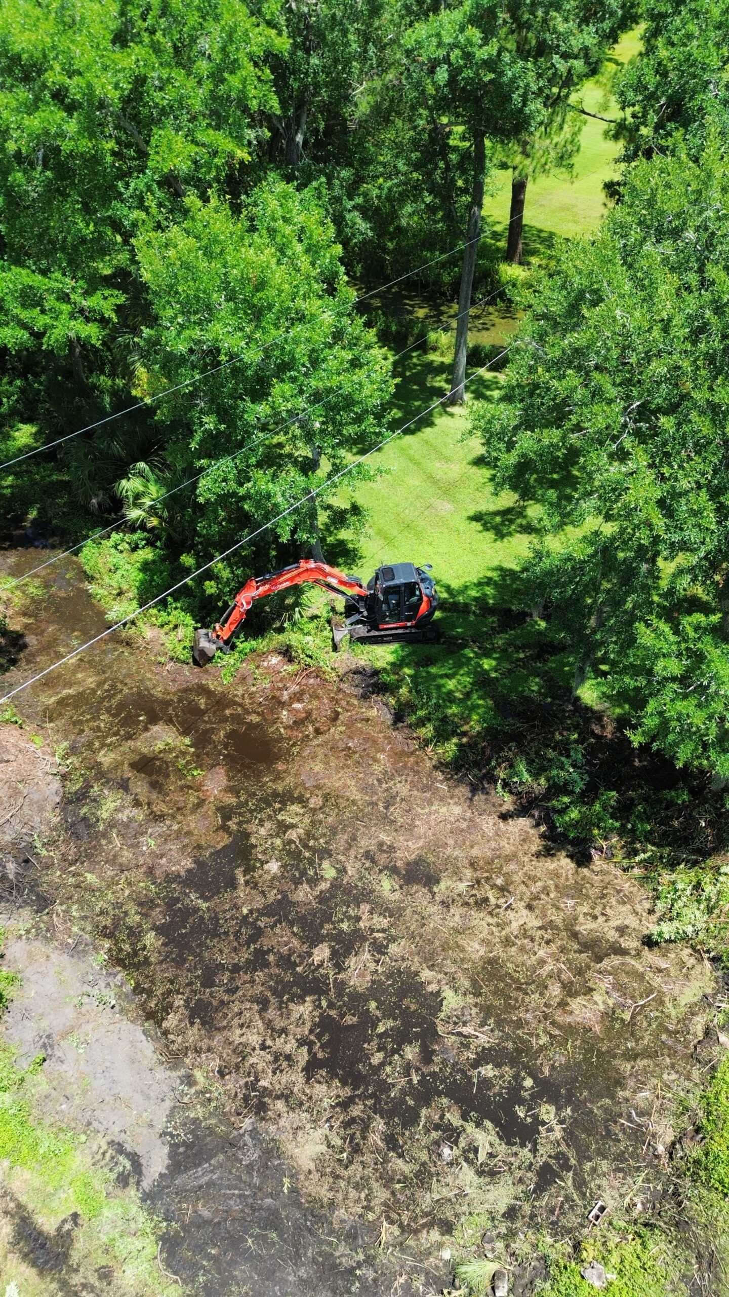 Kubota KX80 excavator clearing and cleaning out a pond in Windermere Florida for drainage improvement